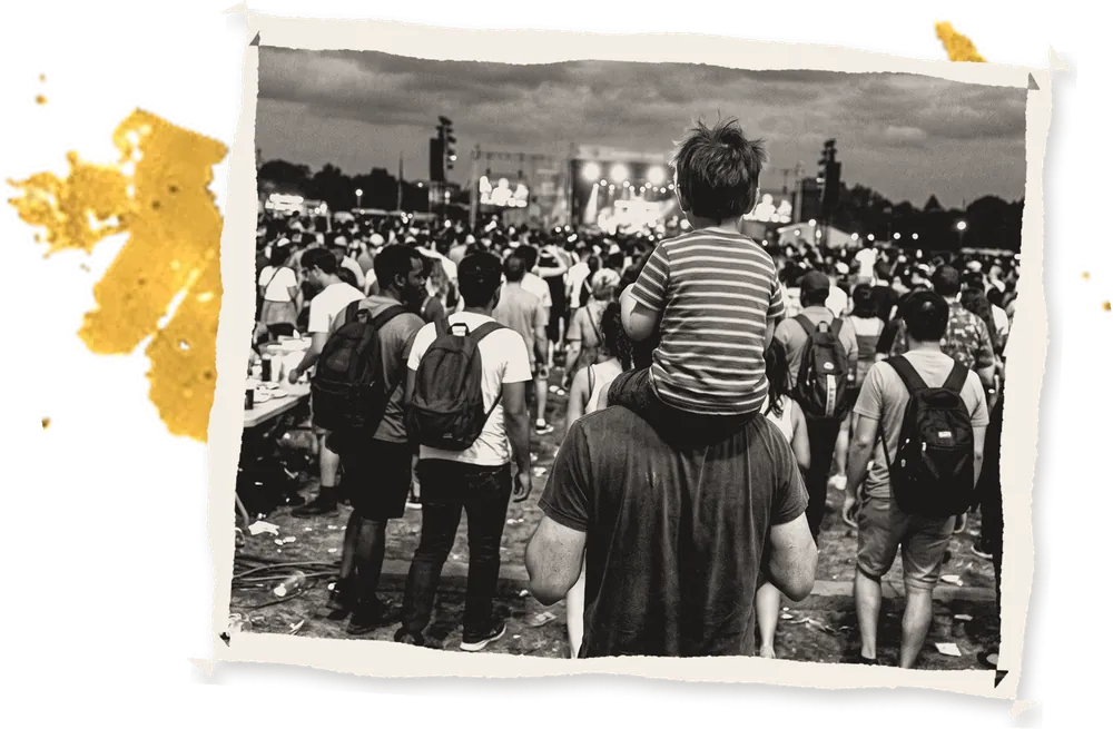 A child on a man's shoulders in an evening festival crowd